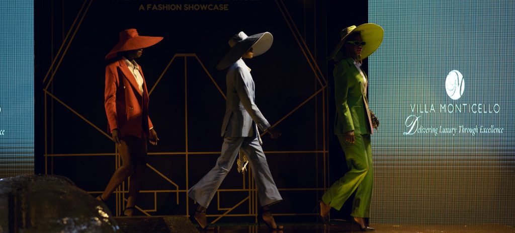 Models walking on stage during a fashion show at Villa Monti Cello, showcasing elegant designs and the excitement of the event.